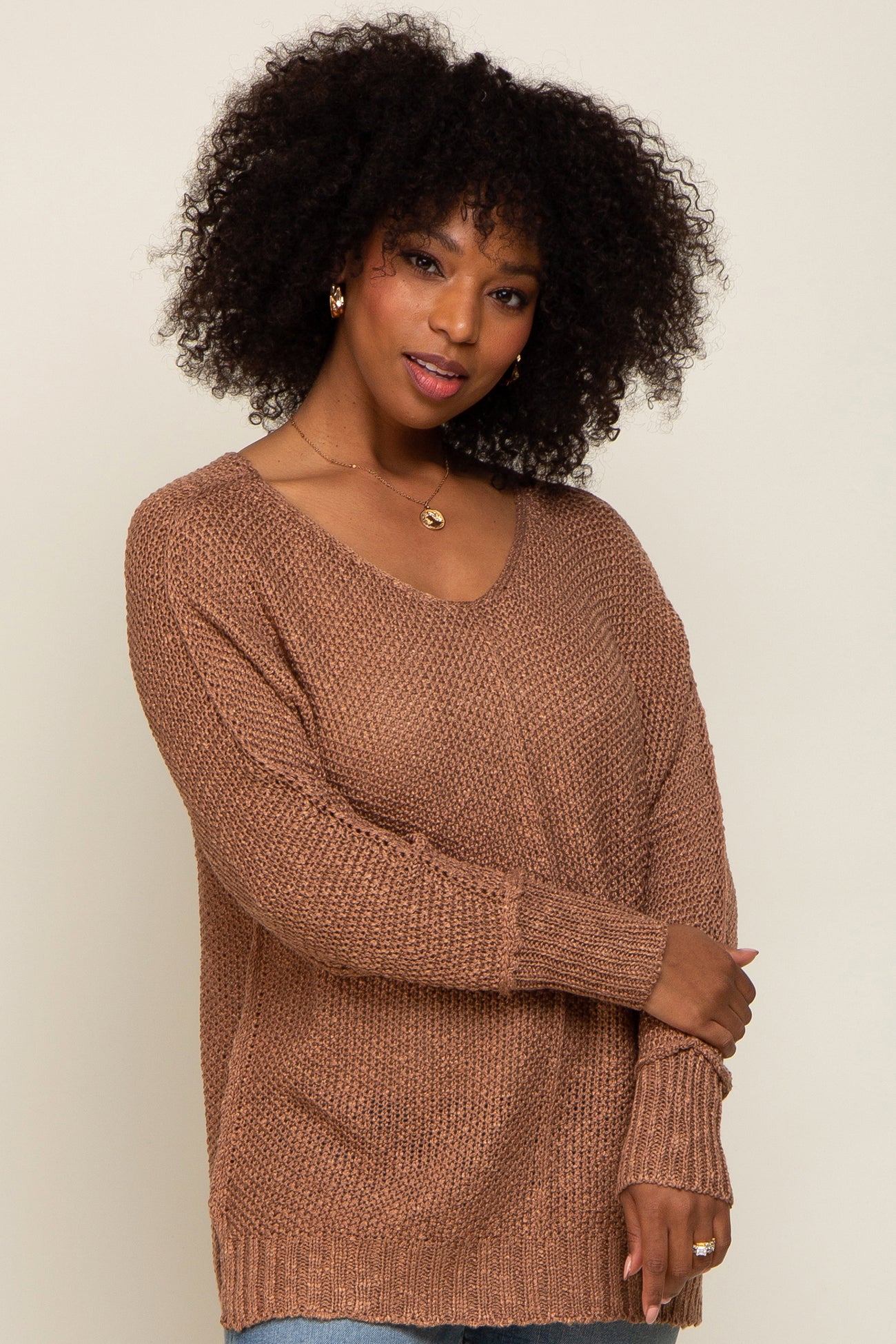woman wearing a brown oversized knit sweater with a v-neckline and long sleeves