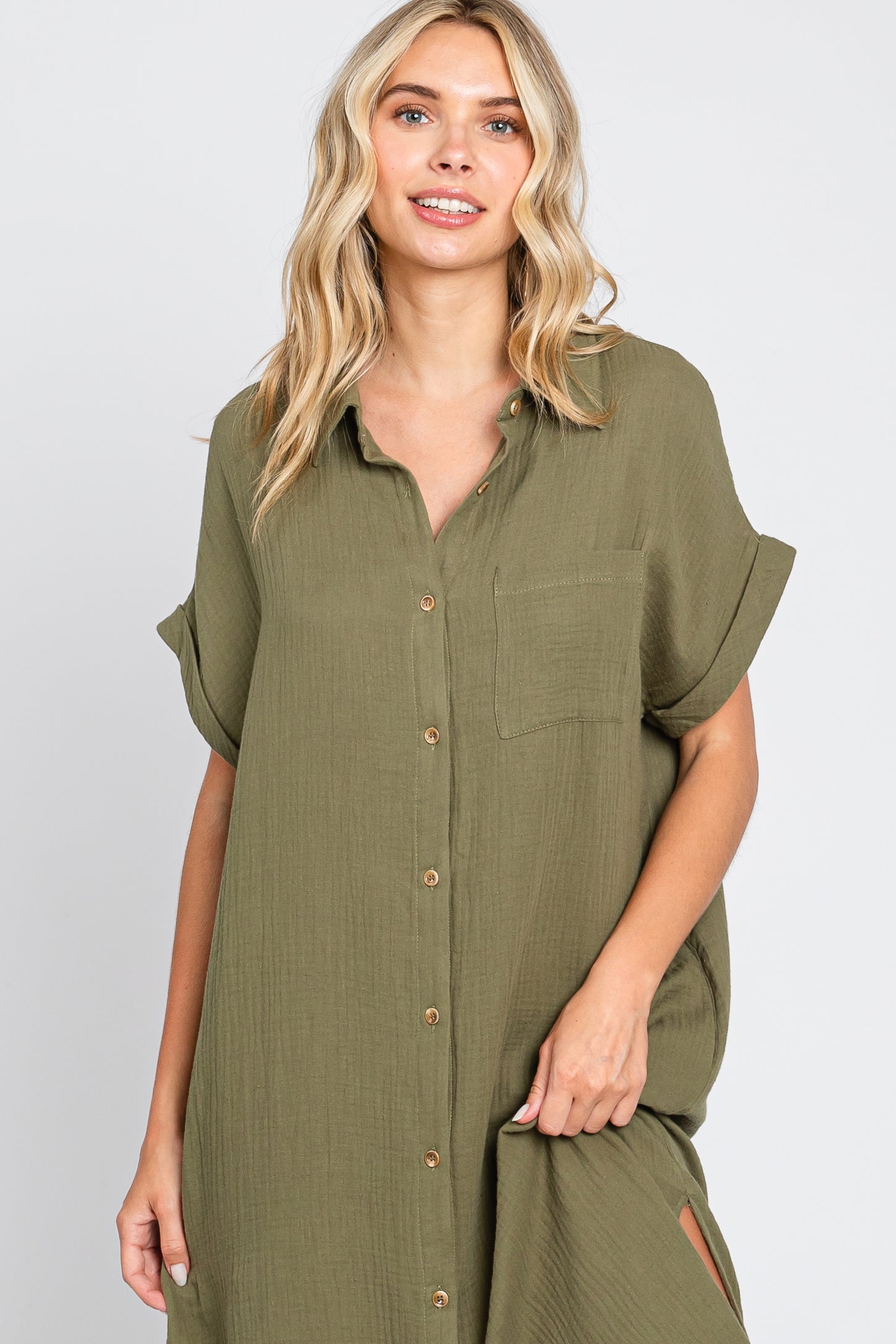 woman wearing an olive green short sleeve button-up dress with a chest pocket and side slits