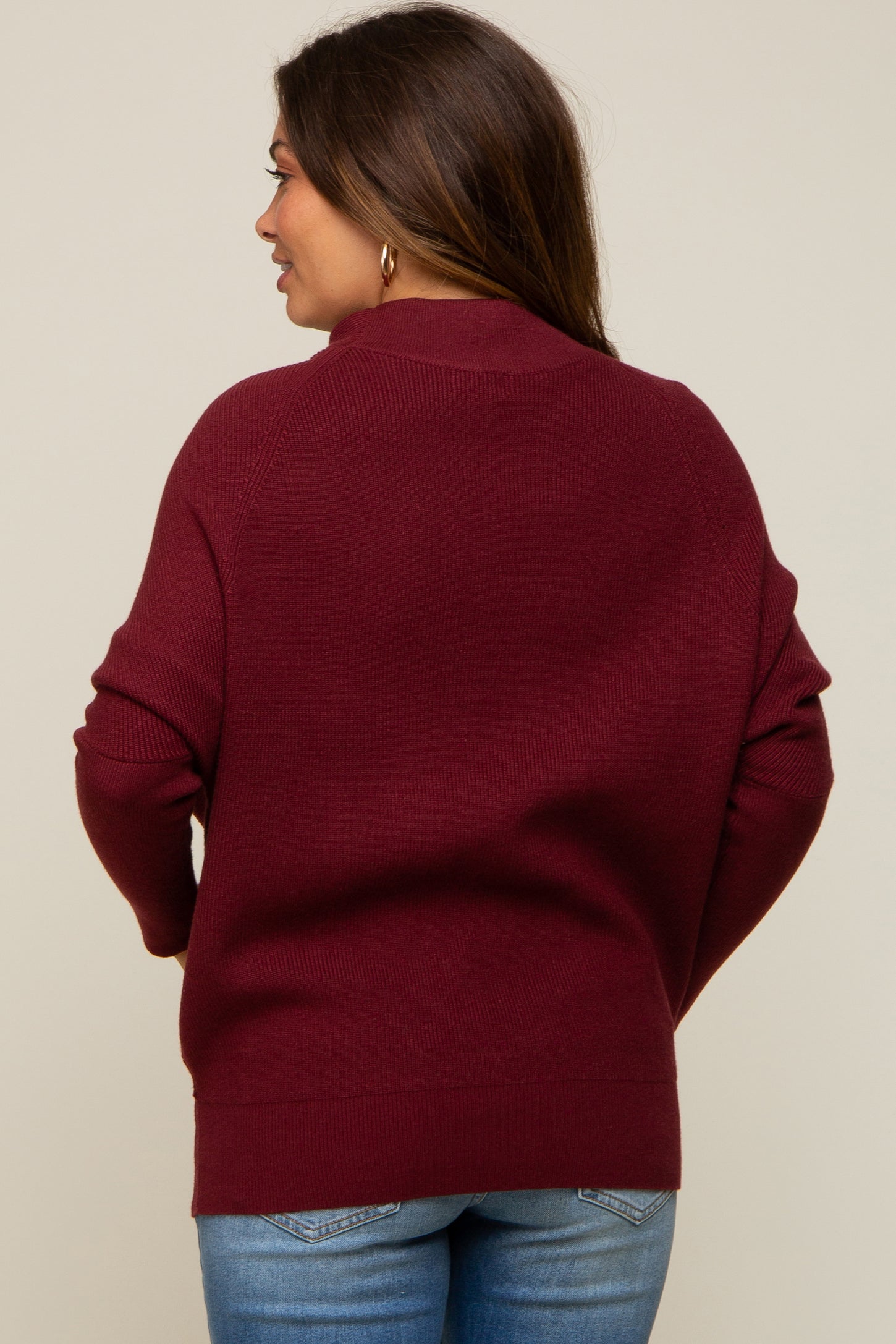 woman wearing a burgundy maternity sweater with a relaxed fit, seen from the back