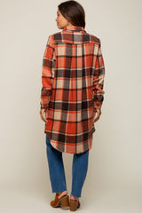 woman wearing a red and brown plaid maternity top, styled as a long shirt, paired with blue jeans and brown shoes