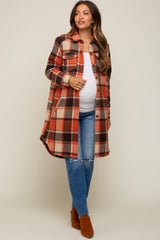 woman wearing a plaid maternity shirt jacket in orange, black, and cream, paired with distressed jeans and brown ankle boots, showing baby bump