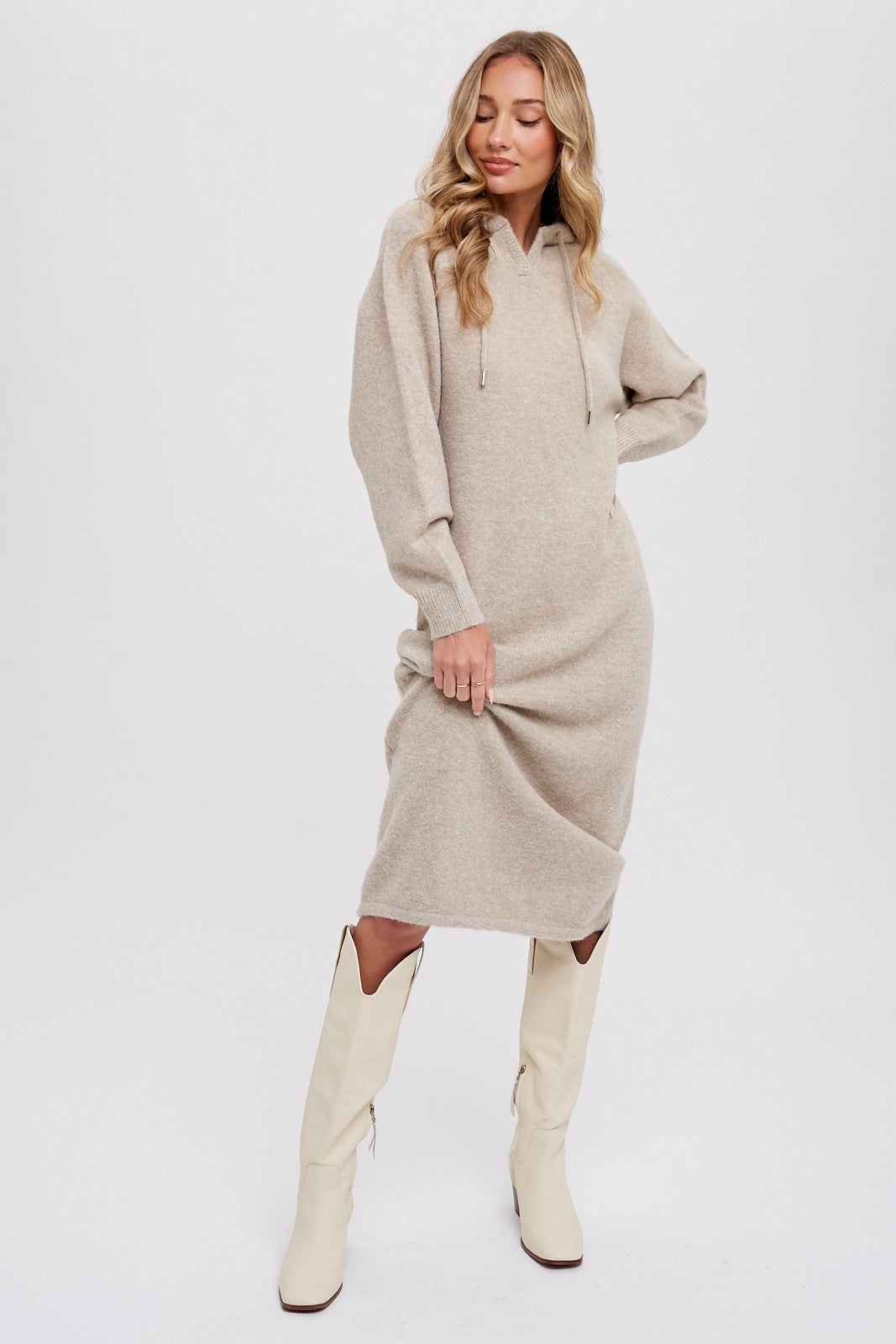 woman wearing a beige hooded sweater dress and white knee-high boots
