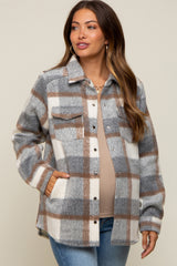 woman wearing a grey and white plaid flannel jacket over a beige maternity top and jeans, showing her baby bump