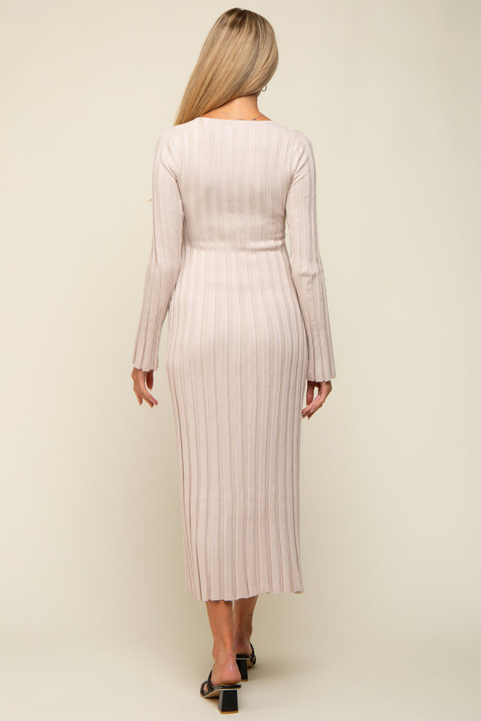 woman wearing a light pink ribbed maternity dress with long sleeves, showing a fitted silhouette and mid-calf length