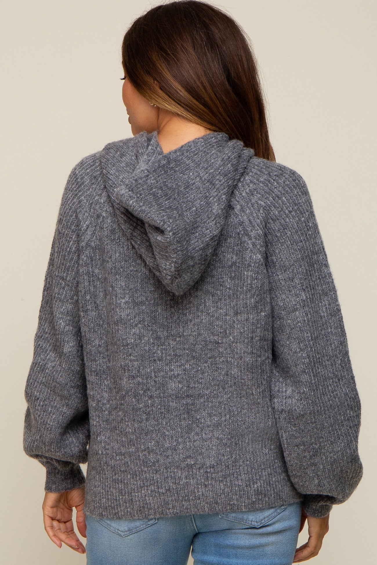 woman wearing a gray maternity hoodie sweater with a relaxed fit and a hood, viewed from the back