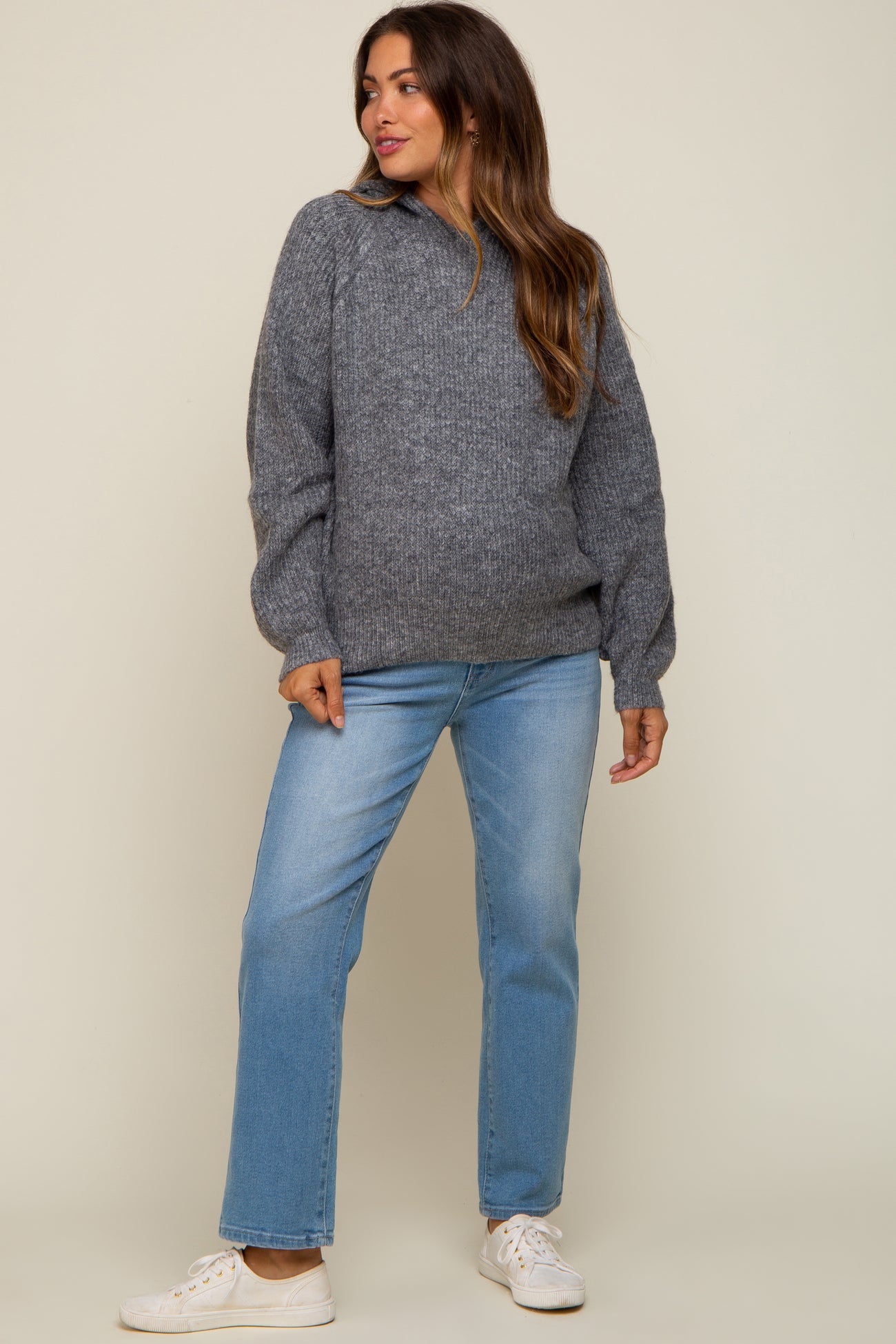 woman wearing a gray maternity sweater with puff sleeves and light blue maternity jeans
