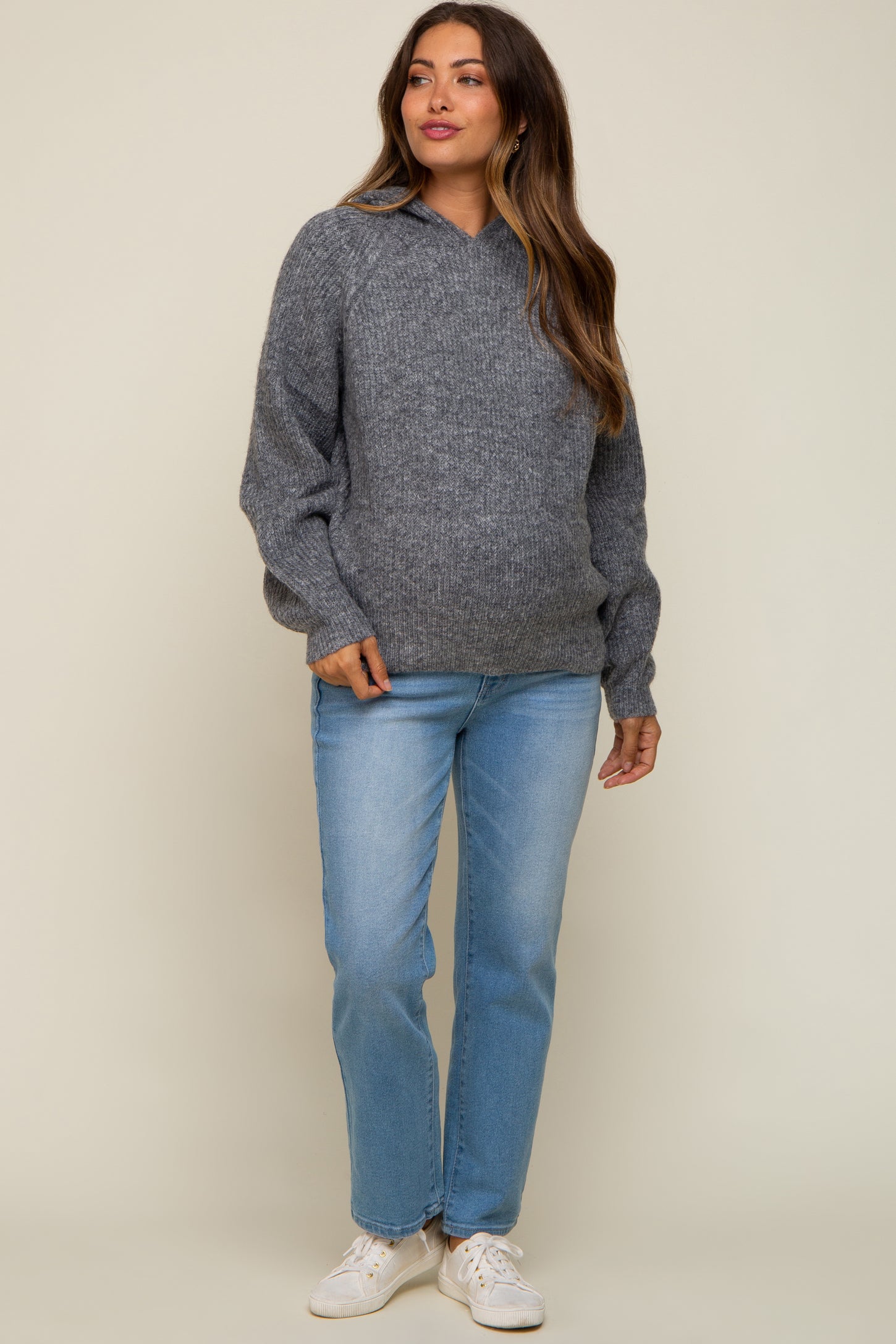 woman wearing a gray maternity sweater with a v-neck and balloon sleeves paired with light blue jeans