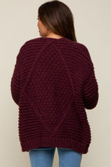 woman wearing a burgundy maternity sweater with a textured design and relaxed fit, featuring a diamond pattern on the back