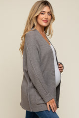 woman wearing a grey knitted maternity cardigan and holding her baby bump