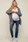 woman wearing a gray open front cardigan over a white maternity top, showing her baby bump, paired with blue jeans and white sneakers