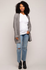 woman wearing a gray cardigan over a white top, paired with distressed jeans and black ankle boots