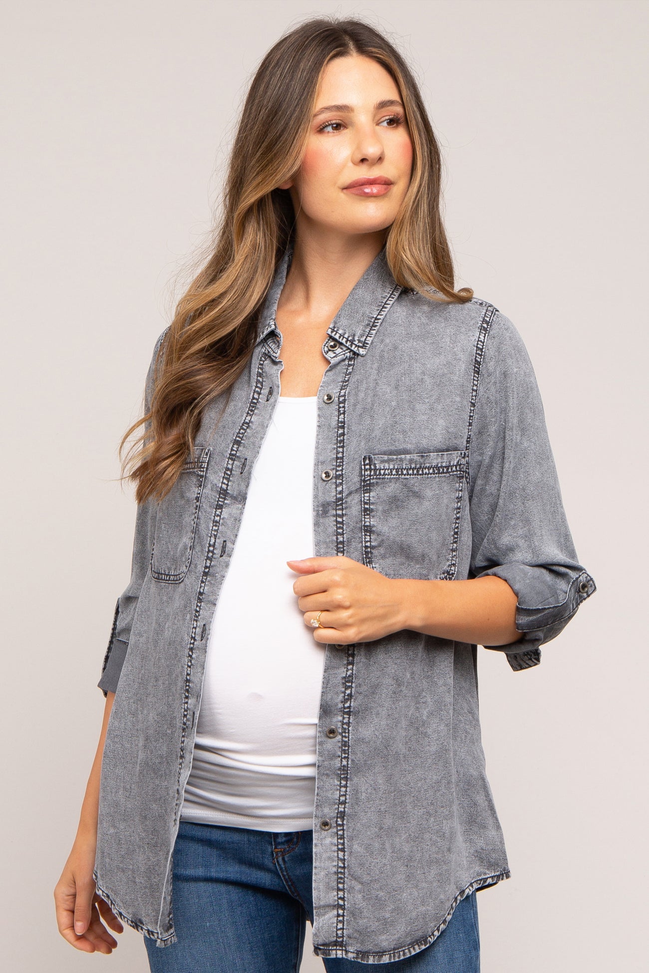 woman wearing a gray denim maternity shirt with rolled sleeves and a visible baby bump