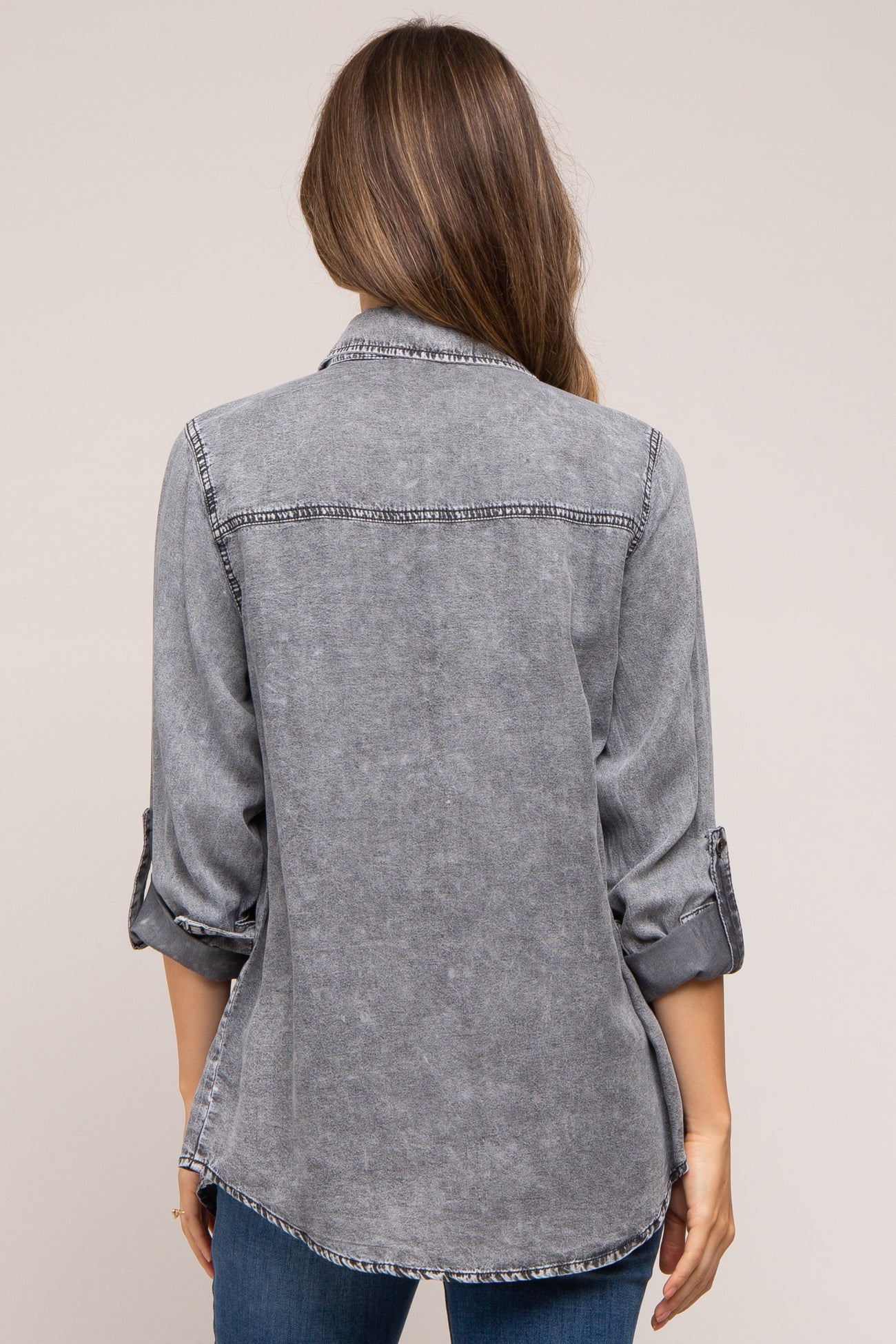 woman wearing a gray denim maternity shirt with rolled-up sleeves, viewed from the back