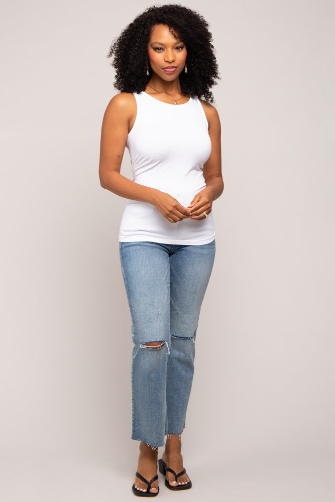 woman wearing a white sleeveless top and light blue ripped jeans with sandals
