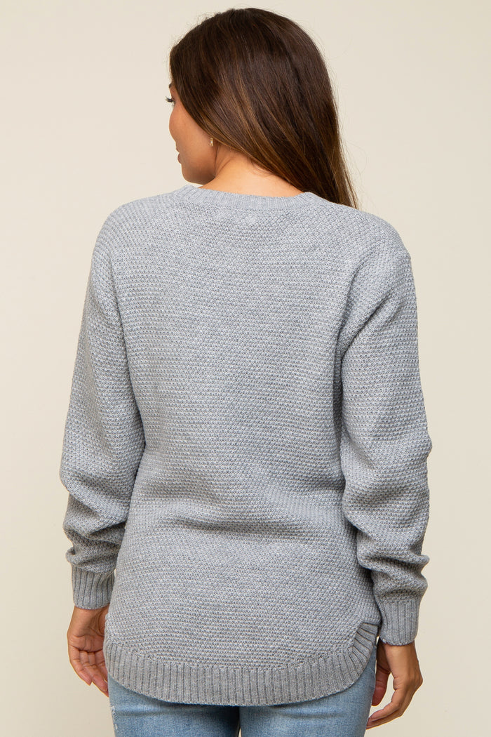 woman wearing a grey maternity sweater with a textured knit and longer back hem