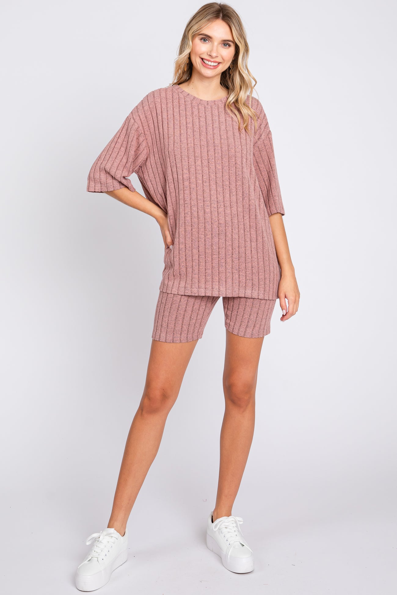 woman wearing a mauve ribbed knit oversized top and matching shorts with white sneakers