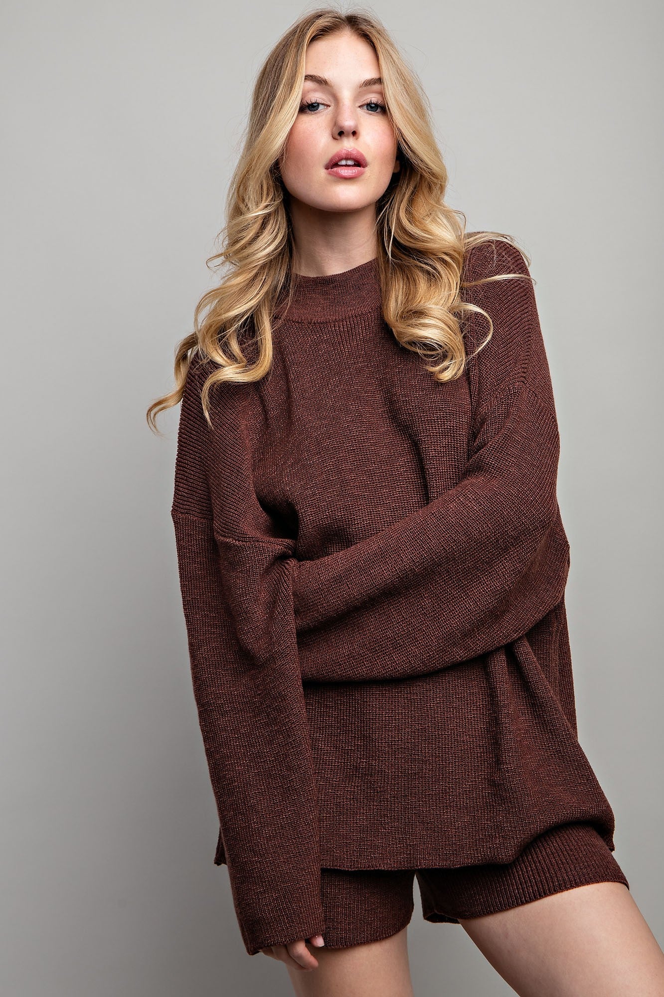 woman wearing a burgundy oversized knitted sweater with long sleeves and matching shorts