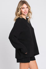 woman wearing an oversized black knit sweater styled with matching black shorts
