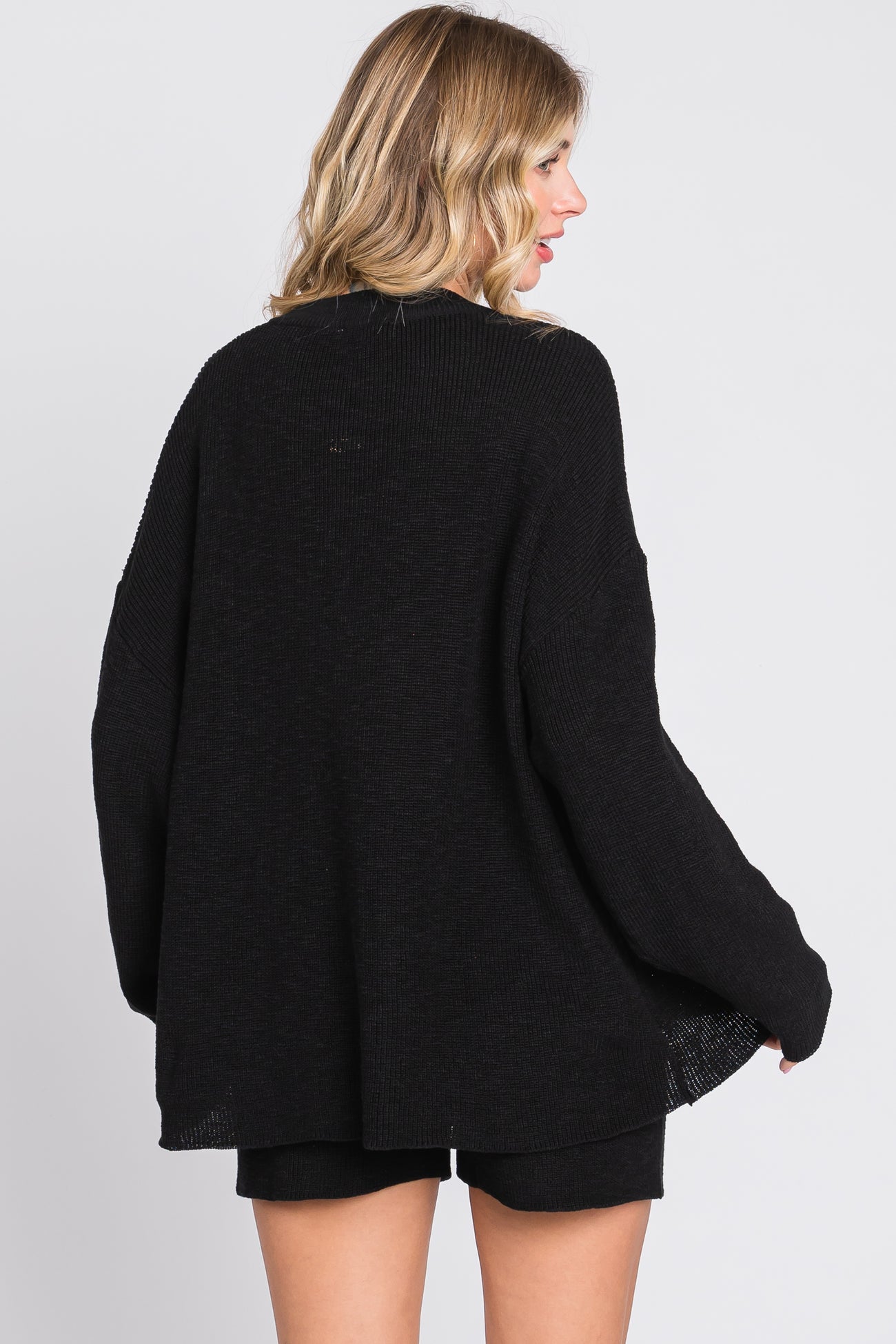 woman wearing a black oversized sweater with a loose fit and long sleeves, seen from the back