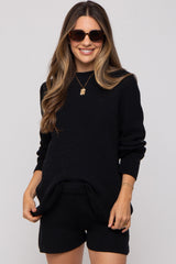 woman wearing a black maternity sweater and shorts set with a relaxed fit and sunglasses, showcasing her baby bump
