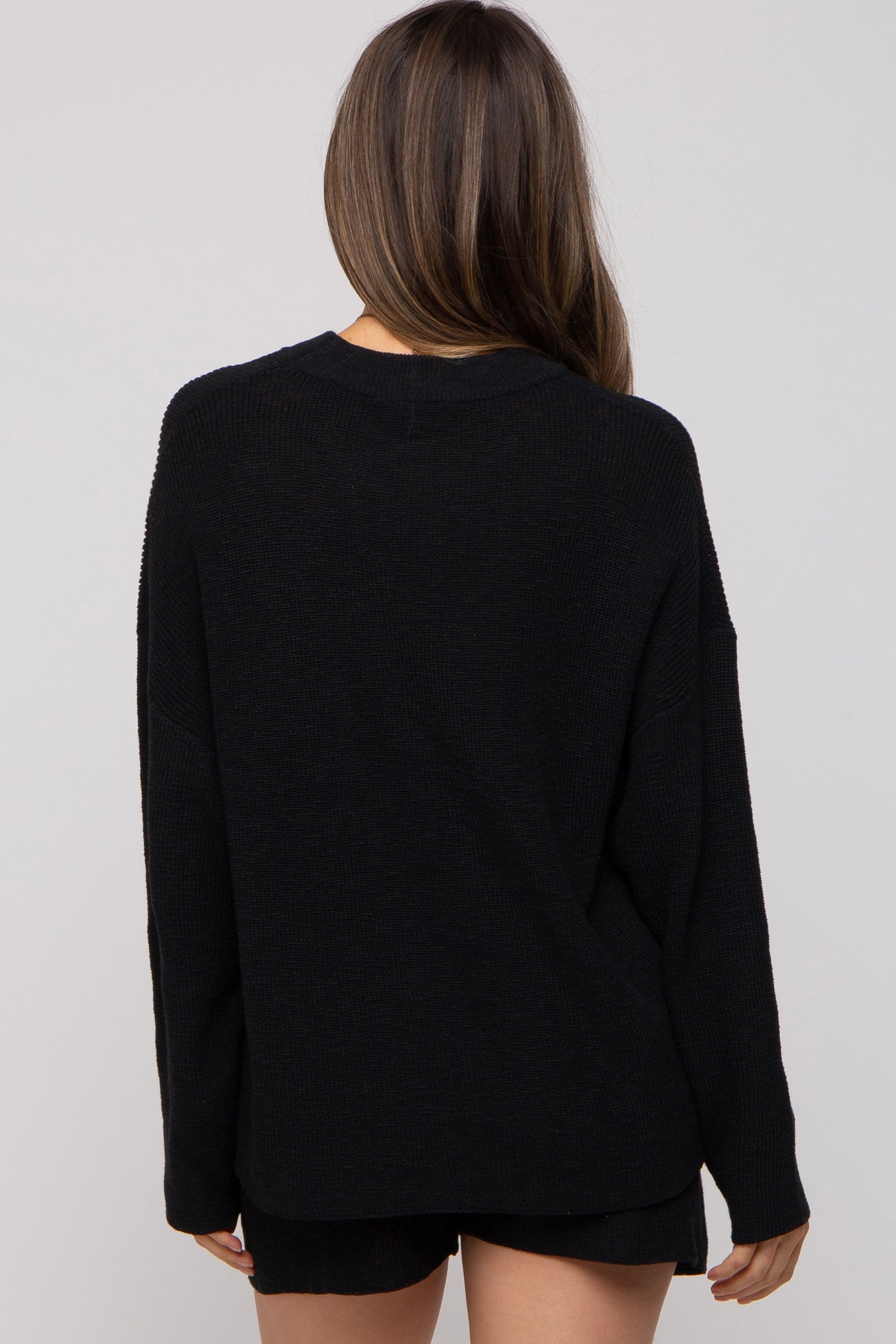 woman wearing a black oversized maternity sweater, shown from the back
