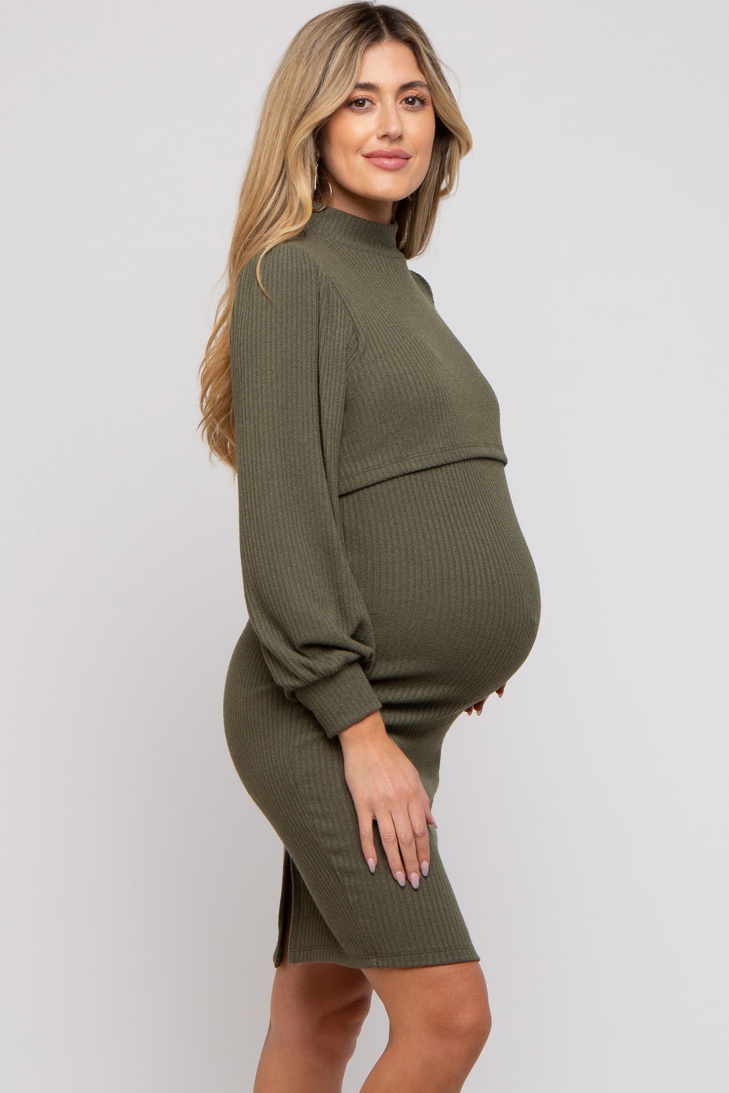 woman wearing an olive green ribbed maternity dress with long sleeves and a fitted silhouette, showcasing her baby bump