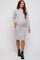 woman wearing a light gray long sleeve maternity dress with puff sleeves and a baby bump, paired with black ankle boots