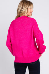 woman wearing a vibrant pink oversized sweater, seen from the back, paired with dark jeans