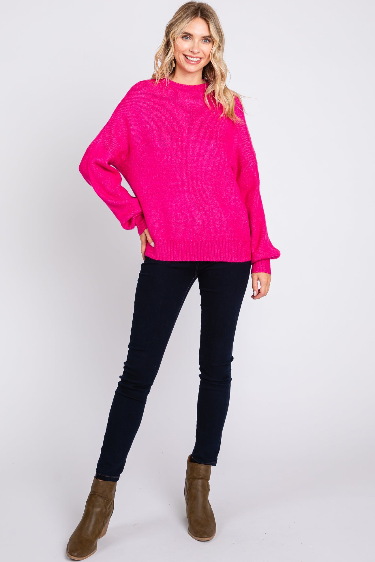 woman wearing a bright pink oversized sweater paired with dark skinny jeans and brown ankle boots