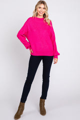 woman wearing a bright pink oversized sweater paired with dark skinny jeans and brown ankle boots