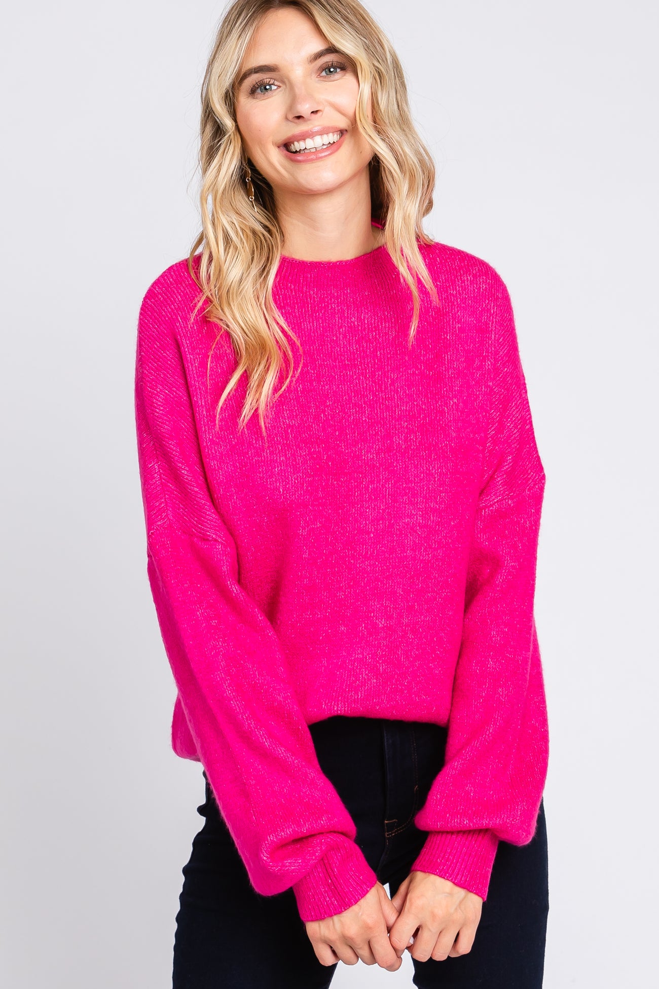 woman wearing a bright pink oversized sweater with balloon sleeves and a relaxed fit
