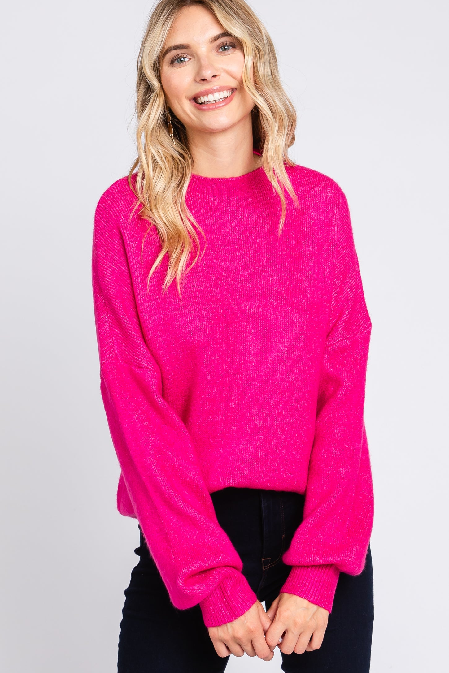 woman wearing a bright pink oversized sweater with balloon sleeves and a relaxed fit