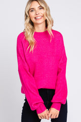woman wearing a bright pink oversized sweater with balloon sleeves and a relaxed fit