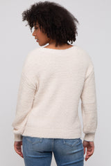 woman wearing a cozy cream-colored textured sweater with long sleeves and a relaxed fit, seen from the back