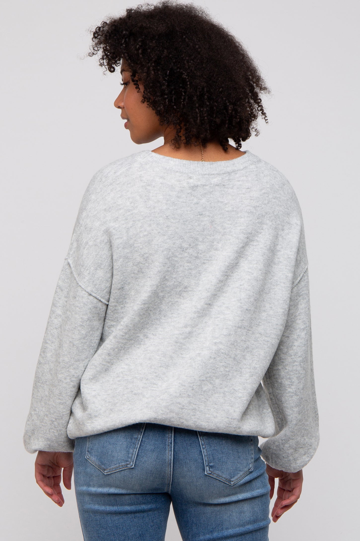 woman wearing a gray oversized sweatshirt with a relaxed fit and back view, paired with blue jeans