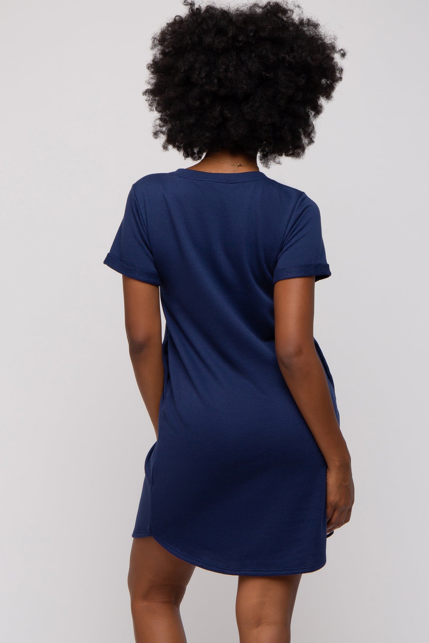 woman wearing a navy blue short sleeve dress, seen from the back with a relaxed fit and rolled sleeves