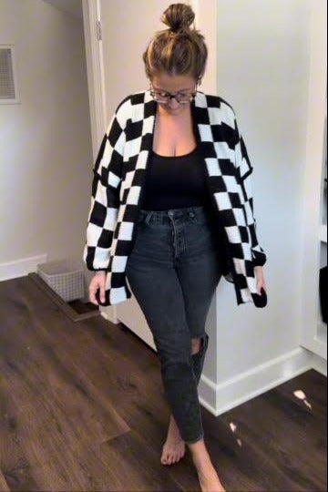 woman wearing a black and white checkered cardigan over a black top and high-waisted gray jeans