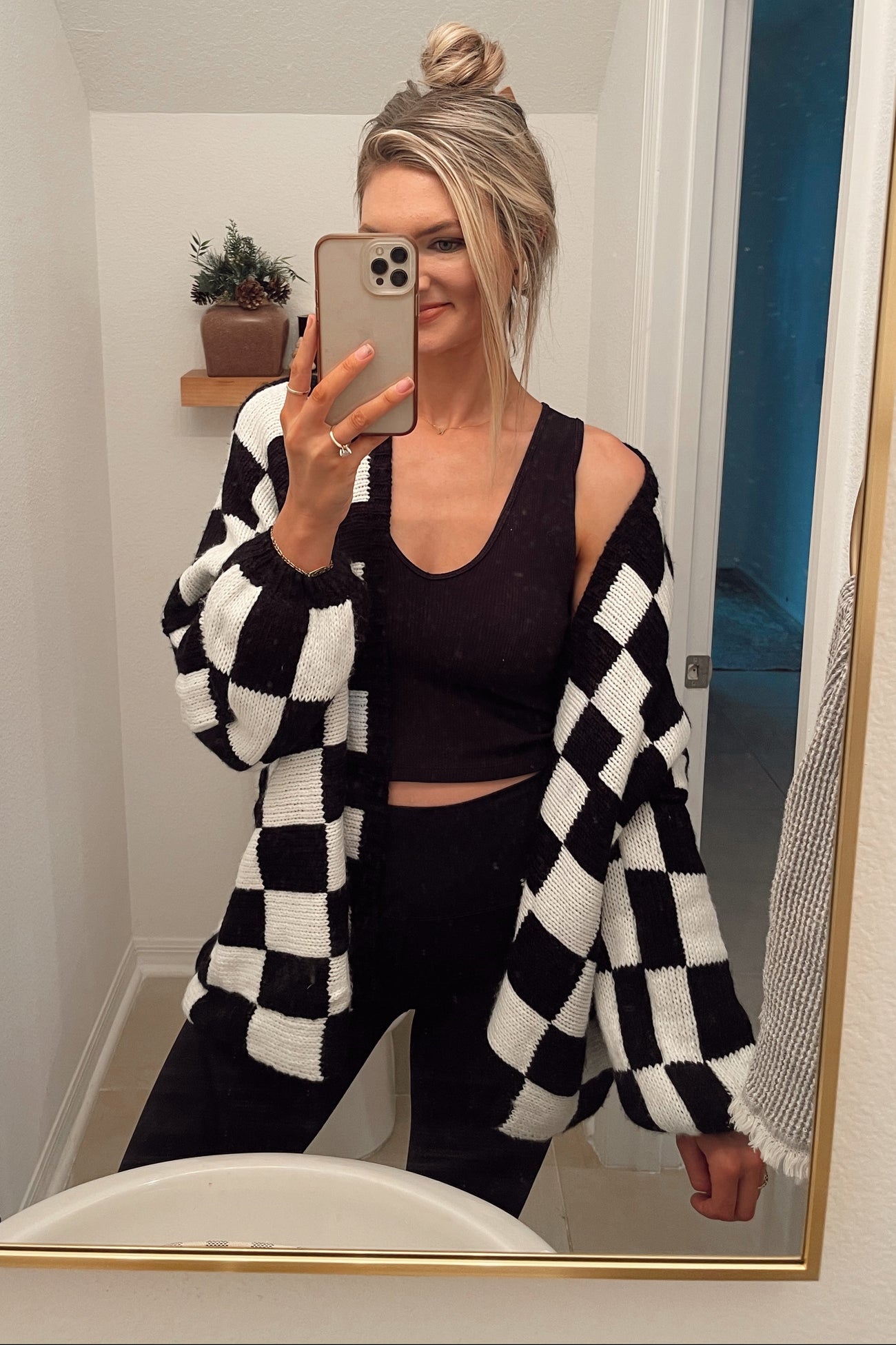 woman wearing a black and white checkered oversized cardigan over a black crop top and black leggings