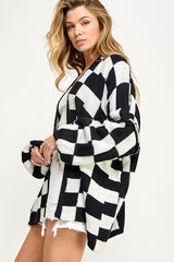woman wearing a black and white checkered oversized cardigan paired with a white top and distressed denim shorts