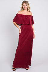 woman wearing a burgundy off-the-shoulder maxi dress with a pleated design and scalloped hem
