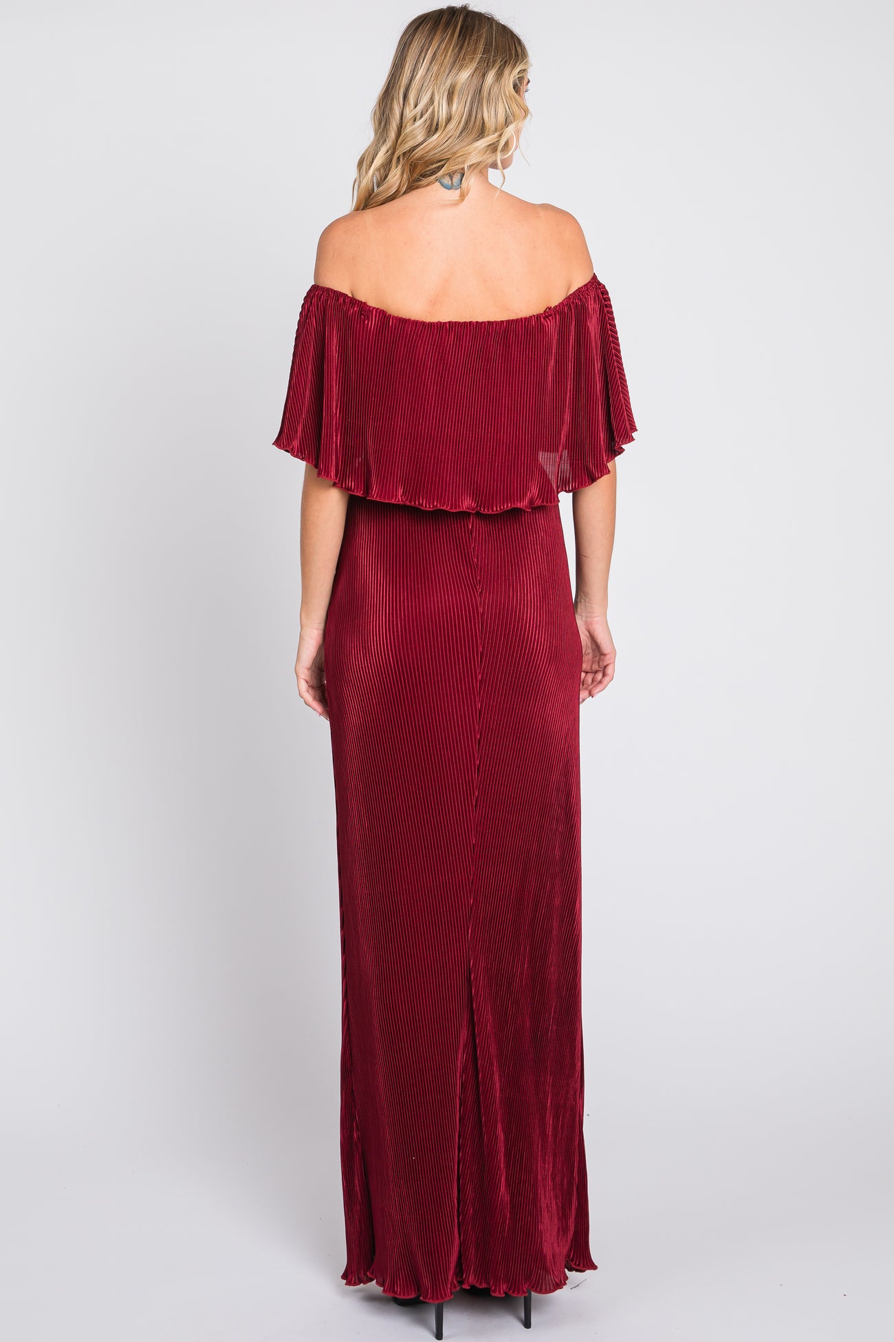 woman wearing a burgundy off-the-shoulder maxi dress with pleated details and a thigh-high slit at the back