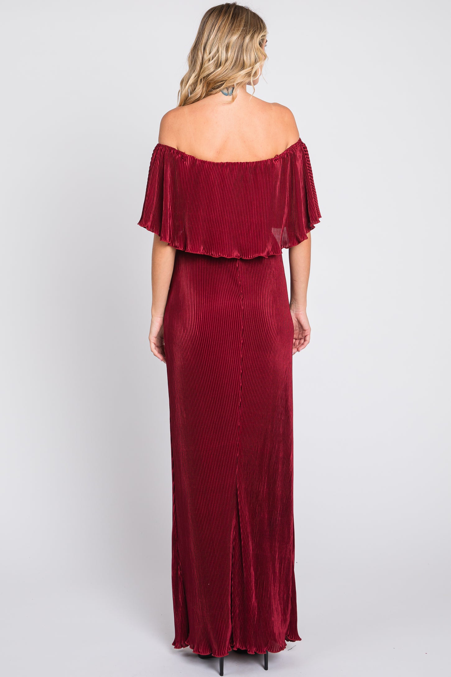 woman wearing a burgundy off-the-shoulder maxi dress with pleated details and a thigh-high slit at the back