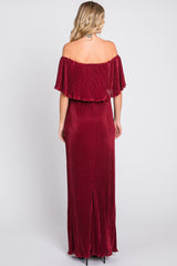 woman wearing a burgundy off-the-shoulder maxi dress with pleated details and a thigh-high slit at the back