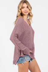 woman wearing a loose-fitting dusty pink v-neck sweater with frayed hem and denim shorts