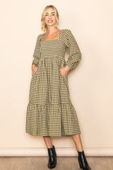 woman wearing a green and beige gingham patterned long sleeve midi dress with a square neckline and pockets
