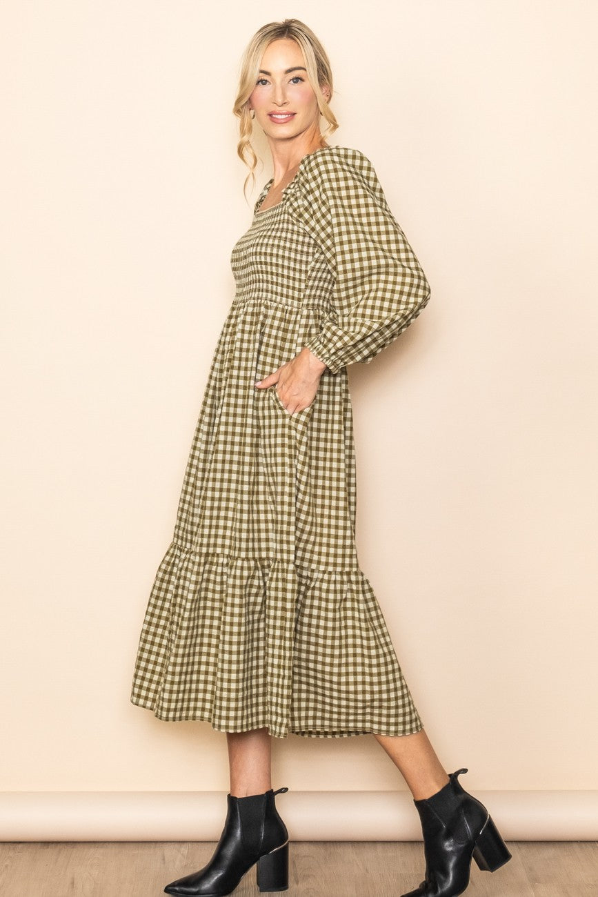 woman wearing a green and beige gingham midi dress with long puff sleeves and a tiered hem