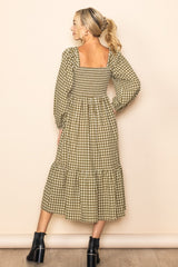 woman wearing a green and beige gingham midi dress with puff sleeves and a tiered skirt, standing with her back to the camera