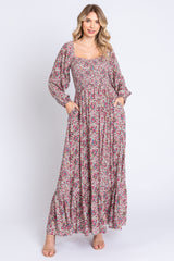 woman wearing a long floral maxi dress with a square neckline and puffed sleeves, featuring pockets