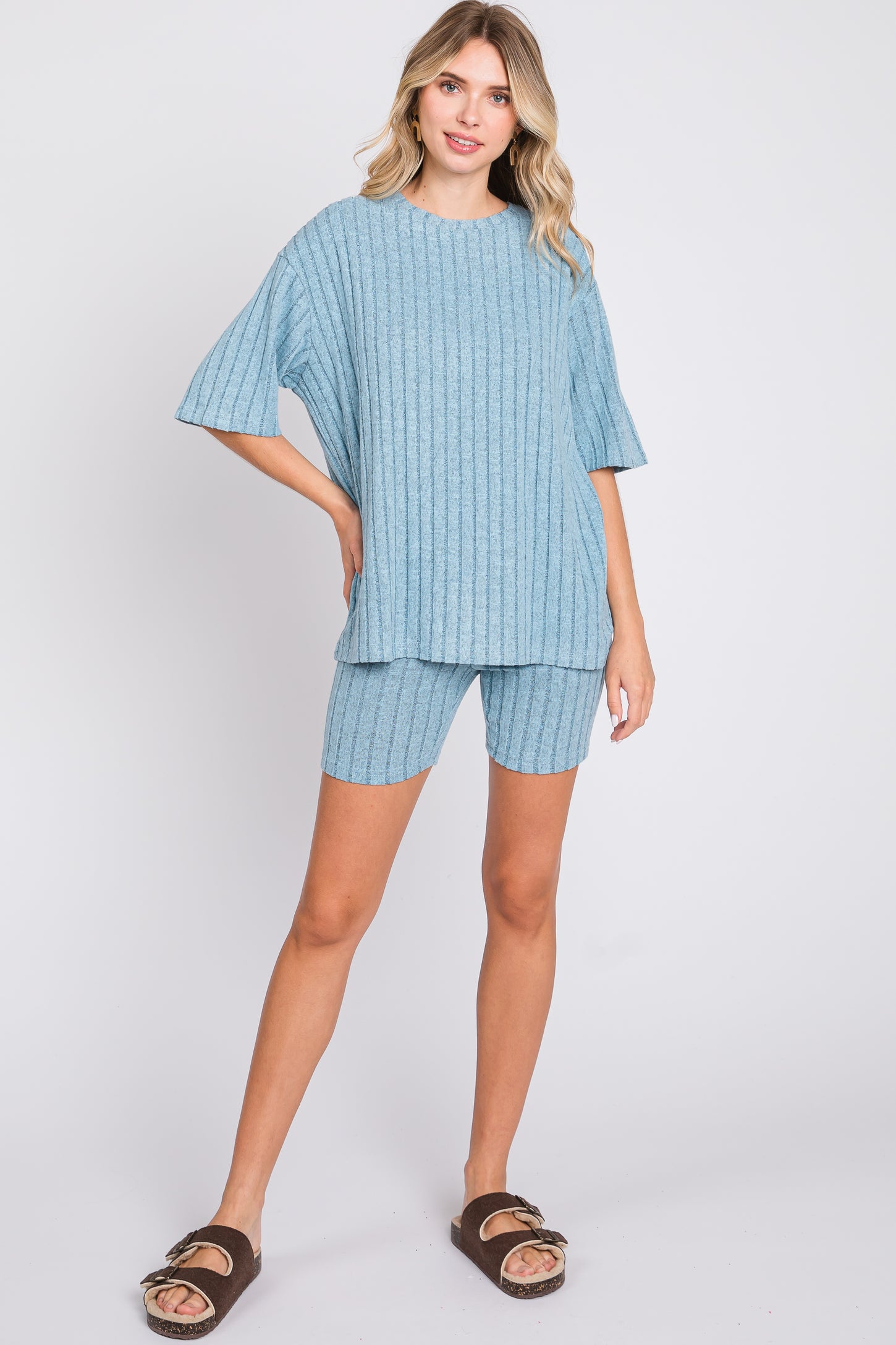 woman wearing a light blue ribbed short sleeve top and matching shorts, styled with brown slide sandals