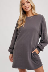 woman wearing a charcoal gray long sleeve sweatshirt dress with side pockets and relaxed fit